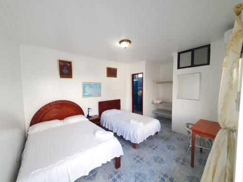 a bedroom with two beds and a table at Hostal Insular in Puerto Villamil