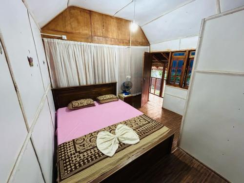 een kleine slaapkamer met een roze bed met bogen bij Athil Cabana in Nilaveli