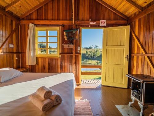 een slaapkamer met een bed met houten wanden en een deur bij Costão do Cambará Pousada Fazenda in Cambará