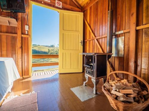 a room with a woodburning stove and a yellow door at Costão do Cambará Pousada Fazenda in Cambara do Sul