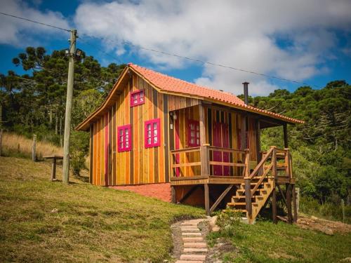 a small wooden house with red windows on a hill at Costão do Cambará Pousada Fazenda in Cambara do Sul
