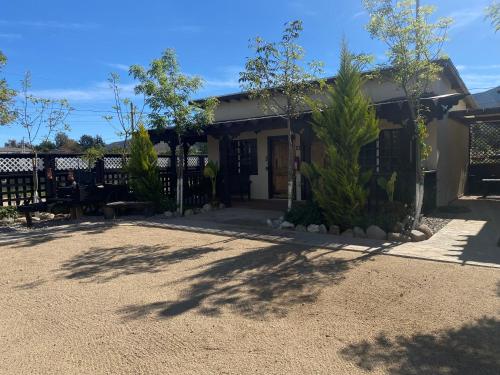 a house with a fence and trees in front of it at Estancita Elena in Valle de Guadalupe