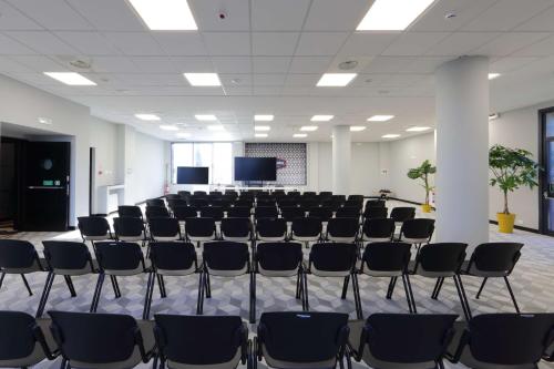 an empty room with chairs and a screen at Hampton by Hilton Rome North Fiano Romano in Fiano Romano