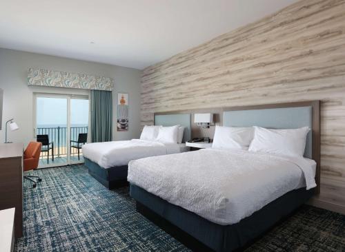 Hampton Inn & Suites Manistee, Mi في مانيستي: غرفة فندقية بسريرين وبلكونة