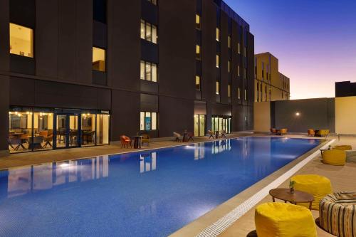une grande piscine en face d'un bâtiment dans l'établissement Hampton By Hilton Sharma - NC1, à Khuraybah