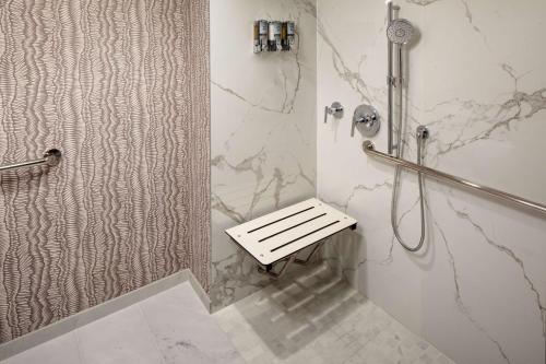 a walk in shower with a bench in a bathroom at Whitney Peak Hotel Reno, Tapestry Collection by Hilton in Reno