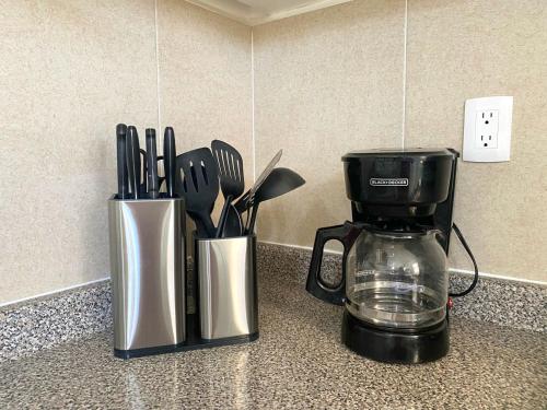 a kitchen counter with a coffee maker and utensils at CASABONITA fte alberca, AirAc in Alpuyeca