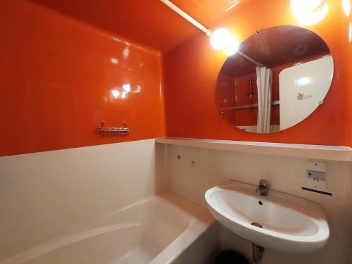 La salle de bains orange est pourvue d'un lavabo et d'un miroir. dans l'établissement Résidence Belles Challes - Studio 4 personnes à Arc 1800 skis aux pieds et proche des commerces dans le village du Charvet MAE-1822, à Arc 1800