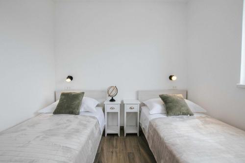 Duas camas num quarto com paredes brancas em Apartments with a parking space Trogir - 22616 em Trogir