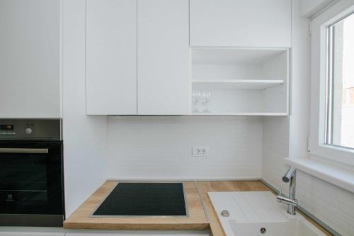 uma cozinha com armários brancos e um forno preto em Apartments with a parking space Trogir - 22616 em Trogir