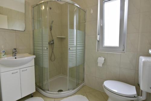 La salle de bains est pourvue d'une douche, de toilettes et d'un lavabo. dans l'établissement Apartments by the sea Umag - 22628, à Umag