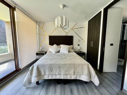 Un dormitorio con una cama grande y una lámpara de araña. en Nuevo Depto en ubicación privilegiada en Santiago