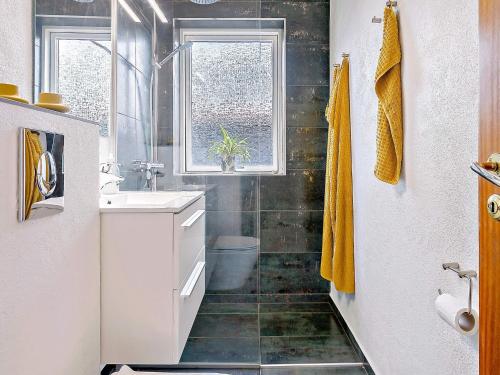 a bathroom with a sink and a toilet and a window at Holiday home Skagen XL in Skagen