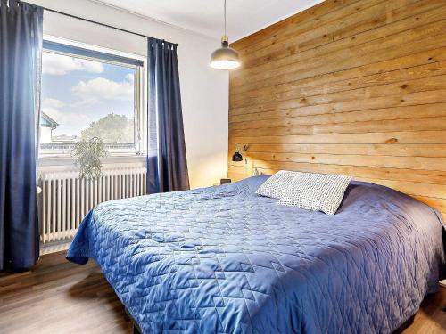 a bedroom with a blue bed with a wooden wall at Holiday home Skagen XL in Skagen