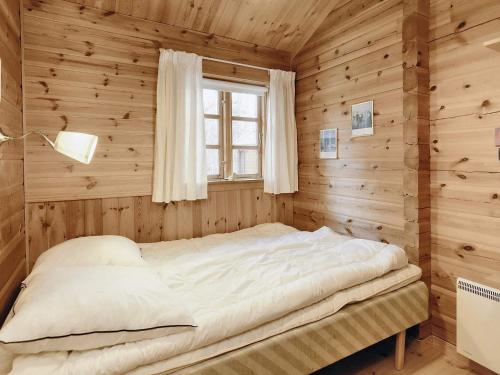 a bed in a wooden room with a window at Holiday home Læsø XII in Læsø