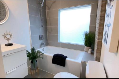 baño con bañera, aseo y ventana en Cozy Private Room in amazing Bungalow, en Toronto