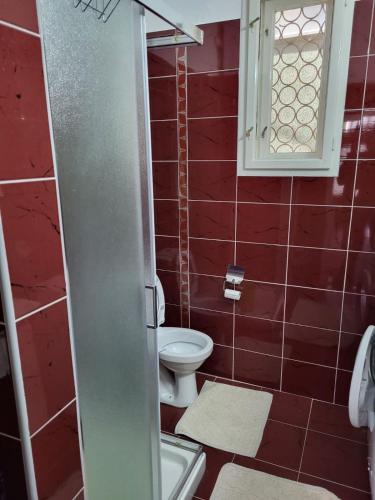 uma casa de banho vermelha com um WC e uma janela em Zelena Oaza em Jagodina