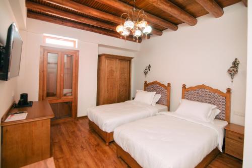 two beds in a room with wooden floors and a chandelier at Istat Boutique Hotel in Bukhara