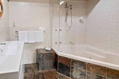 y baño blanco con bañera y ducha. en Clarendon Chalets, en Mount Gambier