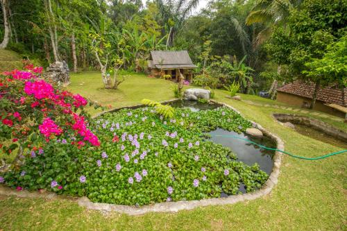 a garden with a pond with flowers and a hose at Pesona Bali Ecolodge by AGATA in Jatiluwih