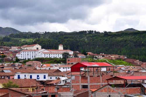 a group of buildings in a town with mountains in the background at The Chusay Rooftop in Cusco