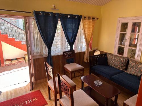 a living room with a couch and a table and chairs at Kanjira house in Ooty