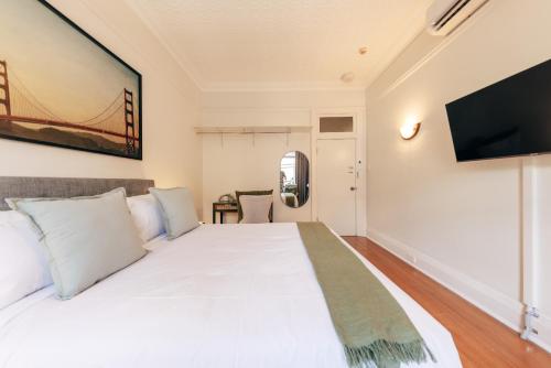 a bedroom with a white bed and a flat screen tv at Gaslight Inn - Adults Only in Sydney