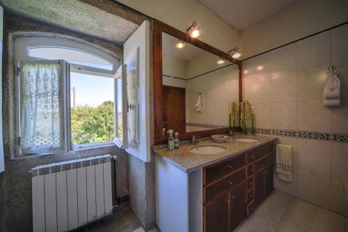 a bathroom with a sink and a mirror and a window at Casa Praia e Campo in Viana do Castelo