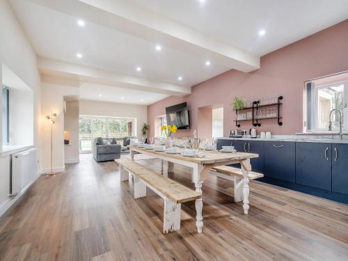 eine Küche und ein Wohnzimmer mit einem Holztisch und einer Bank in der Unterkunft Home Farm - The Coo Shed in Dunragit