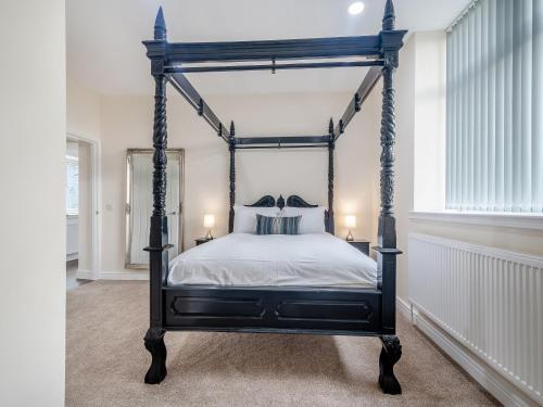 a bedroom with a black canopy bed with white sheets at Home Farm - The Coo Shed in Dunragit