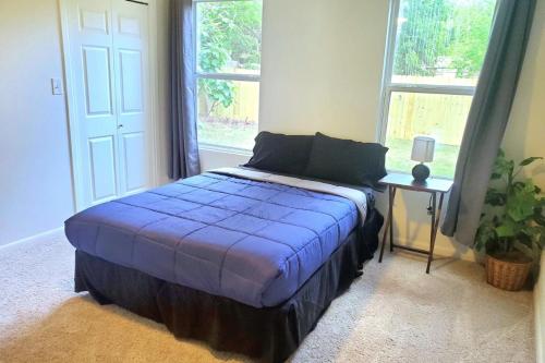 um quarto com uma cama com um cobertor azul e uma janela em Charming Home 5 Min From Downtown & At&t Center em San Antonio