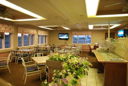 een eetkamer met tafels, stoelen en bloemen bij Country garden hotel in Smoky Lake