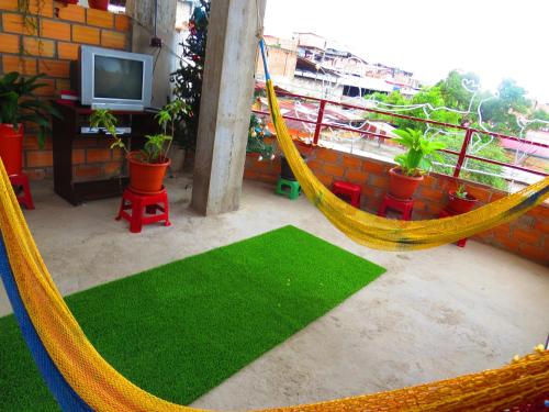a hammock on a balcony with a television and plants at Hostel Flor del Valle in Tarapoto