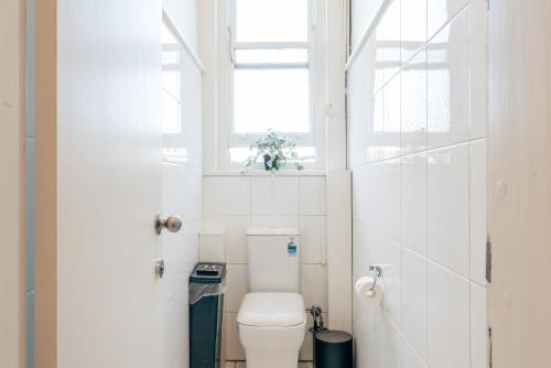 a white bathroom with a toilet and a window at Gaslight Inn - Adults Only in Sydney