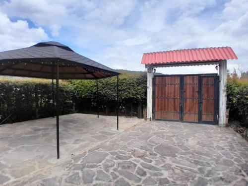 a patio with an umbrella and a gate at Cabaña Villa Eugenia - Paipa in Paipa