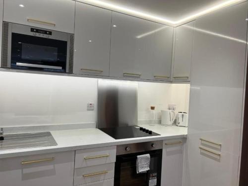 a kitchen with white cabinets and a stove top oven at Manhattan Luxury Suites in Bradford