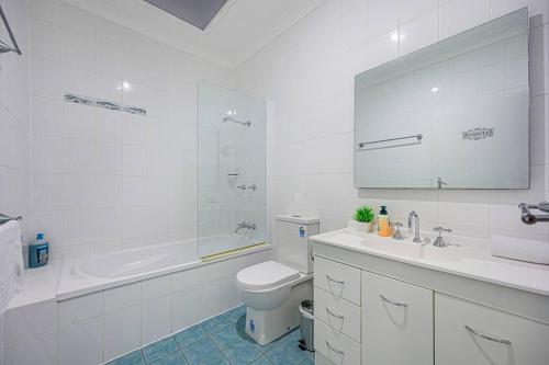 a bathroom with a toilet and a tub and a sink at Penrith｜Nepean hospital｜4Br house｜wifi&Parking in Penrith