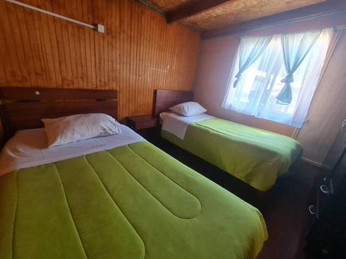 1 dormitorio con 2 camas y ventana en Cabaña Alejandra, en Puerto Puyuhuapi