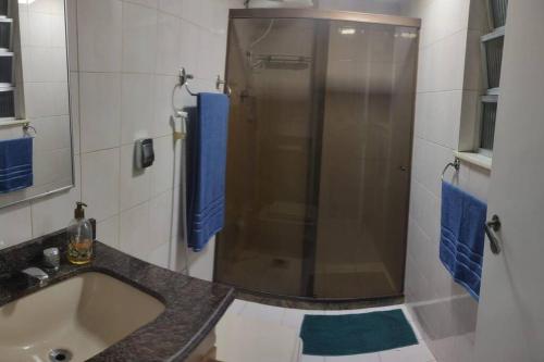 a bathroom with a sink and a shower with blue towels at Lindo apartamento em Icaraí perto de tudo. in Niterói