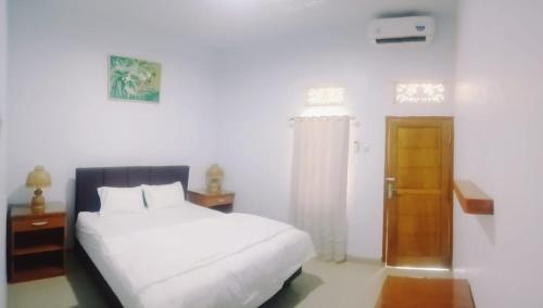 a bedroom with a white bed and a wooden door at Swan Homestay in Labuhanpandan