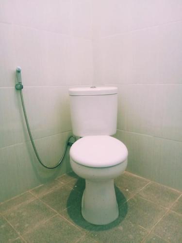 a white toilet in a bathroom with a hose at Swan Homestay in Labuhanpandan
