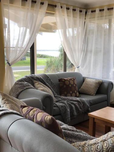 a living room with a couch in front of a window at Jen’s Beach House - easy walk to the Ocean, Colourpatch Cafe by the river in Augusta