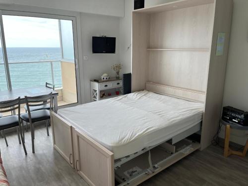 - une chambre avec un lit, une table et un balcon dans l'établissement Studio cosy avec balcon face à la plage - Les Sables-d'Olonne - FR-1-197-275, à Les Sables-dʼOlonne