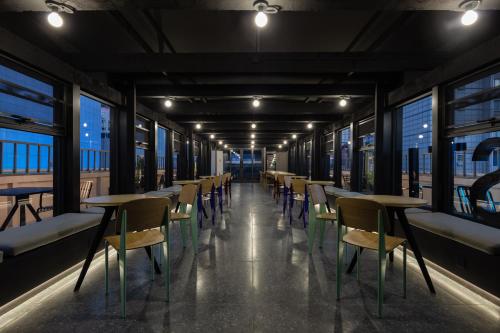 a row of tables and chairs in a room with windows at Chengdu Desti Youth Park Hostel Taiguli in Chengdu