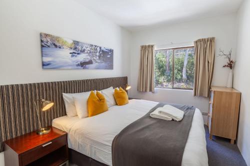 sypialnia z dużym łóżkiem z żółtymi poduszkami w obiekcie Lantern 1 Bedroom Balcony with Village and Mountain View w mieście Thredbo