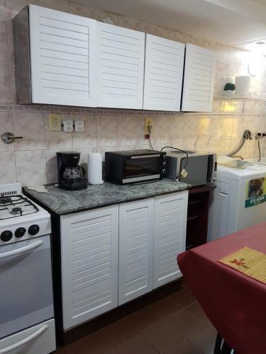 a kitchen with white cabinets and a counter with a microwave at DEPTO CENTRICO Y ACOGEDOR in San Miguel de Tucumán
