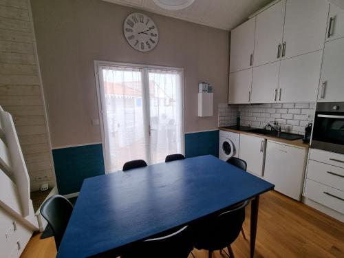 une cuisine avec une table bleue et une horloge murale dans l'établissement Maisonnette rénovée proche plage, centre-ville, avec terrasse et parking privé - FR-1-22-175, à La Tranche-sur-Mer