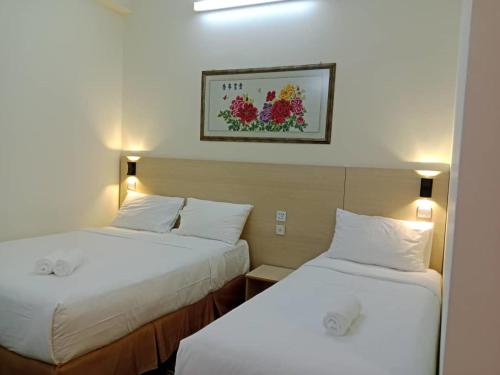 two beds in a hotel room with white sheets at hotel bintang in Kuala Lumpur