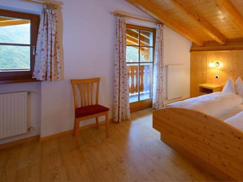 um quarto com uma cama, uma cadeira e uma janela em Holiday apartment Prackfolerhof em Vols am Schlern