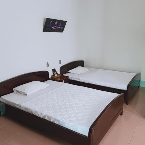 two twin beds in a room with avertisement for at DNTN Khách Sạn Hải Vân in Ha Tien